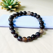 Image of Natural Sulemani Hakik Bracelet with 8mm round black agate beads in a stretchable design, displayed in a circular shape on a white surface