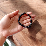 Image of Natural Sulemani Hakik Bracelet with 8mm round black agate beads in a stretchable design, displayed in a circular shape on a white surface