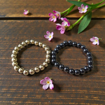 Image of a combo bracelet featuring 8mm golden Pyrite beads and glossy black Obsidian beads arranged side by side on a neutral background