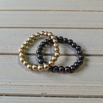 Image of a combo bracelet featuring 8mm golden Pyrite beads and glossy black Obsidian beads arranged side by side on a neutral background