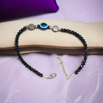 Image of a handcrafted black crystal beads anklet with a central evil eye charm, designed for unisex wear and spiritual protection