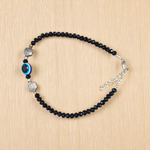 Image of a handcrafted black crystal beads anklet with a central evil eye charm, designed for unisex wear and spiritual protection