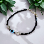 Image of a handcrafted black crystal beads anklet with a central evil eye charm, designed for unisex wear and spiritual protection