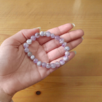 Image of a natural Amethyst bracelet with polished 8mm deep purple beads, arranged in a circular shape on a light background