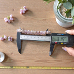 Image of a natural Amethyst bracelet with polished 8mm deep purple beads, arranged in a circular shape on a light background
