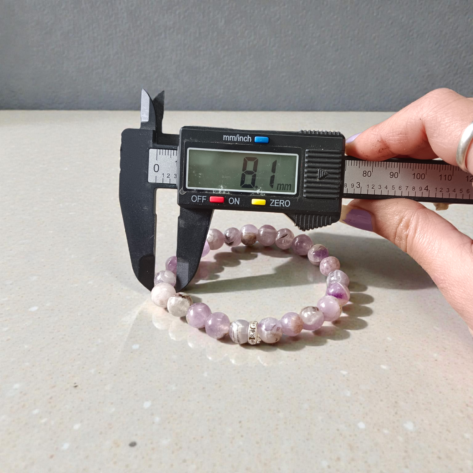 Image of a natural Amethyst bracelet with polished 8mm deep purple beads, arranged in a circular shape on a light background