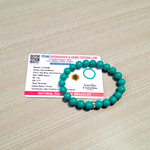 Image of a natural turquoise bracelet with polished 8mm round blue beads and black veining, displayed in a circular shape on a plain background