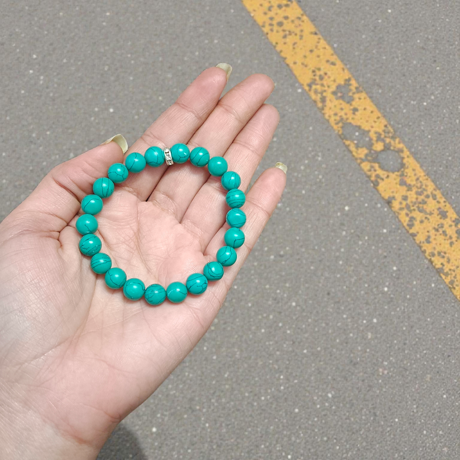 Image of a natural turquoise bracelet with polished 8mm round blue beads and black veining, displayed in a circular shape on a plain background