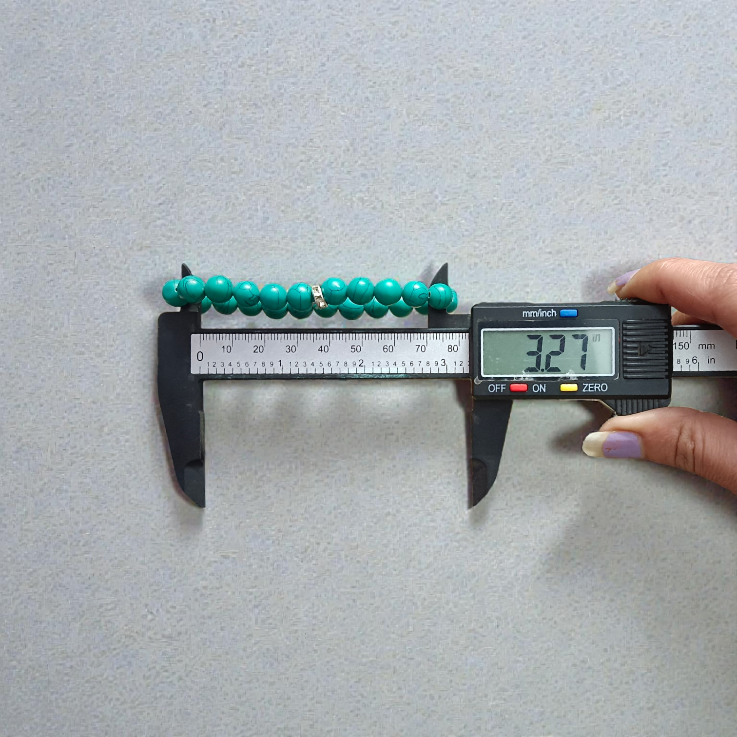 Image of a natural turquoise bracelet with polished 8mm round blue beads and black veining, displayed in a circular shape on a plain background