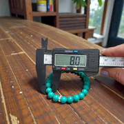 Image of a natural turquoise bracelet with polished 8mm round blue beads and black veining, displayed in a circular shape on a plain background