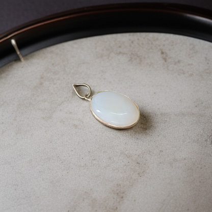 Image of a polished oval Natural Milky Moonstone Pendant on a black adjustable cotton thread, displayed on a neutral background