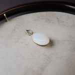 Image of a polished oval Natural Milky Moonstone Pendant on a black adjustable cotton thread, displayed on a neutral background