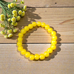 Image of a stretchable Yellow Onyx bracelet with polished 8mm round beads arranged in a circle on a white or neutral background