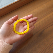 Image of a stretchable Yellow Onyx bracelet with polished 8mm round beads arranged in a circle on a white or neutral background