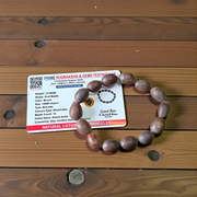 Image of two adjustable spiritual bracelets – one made with white Vaijanti seeds and the other with brown Kamal Gutta beads – displayed on a natural surface