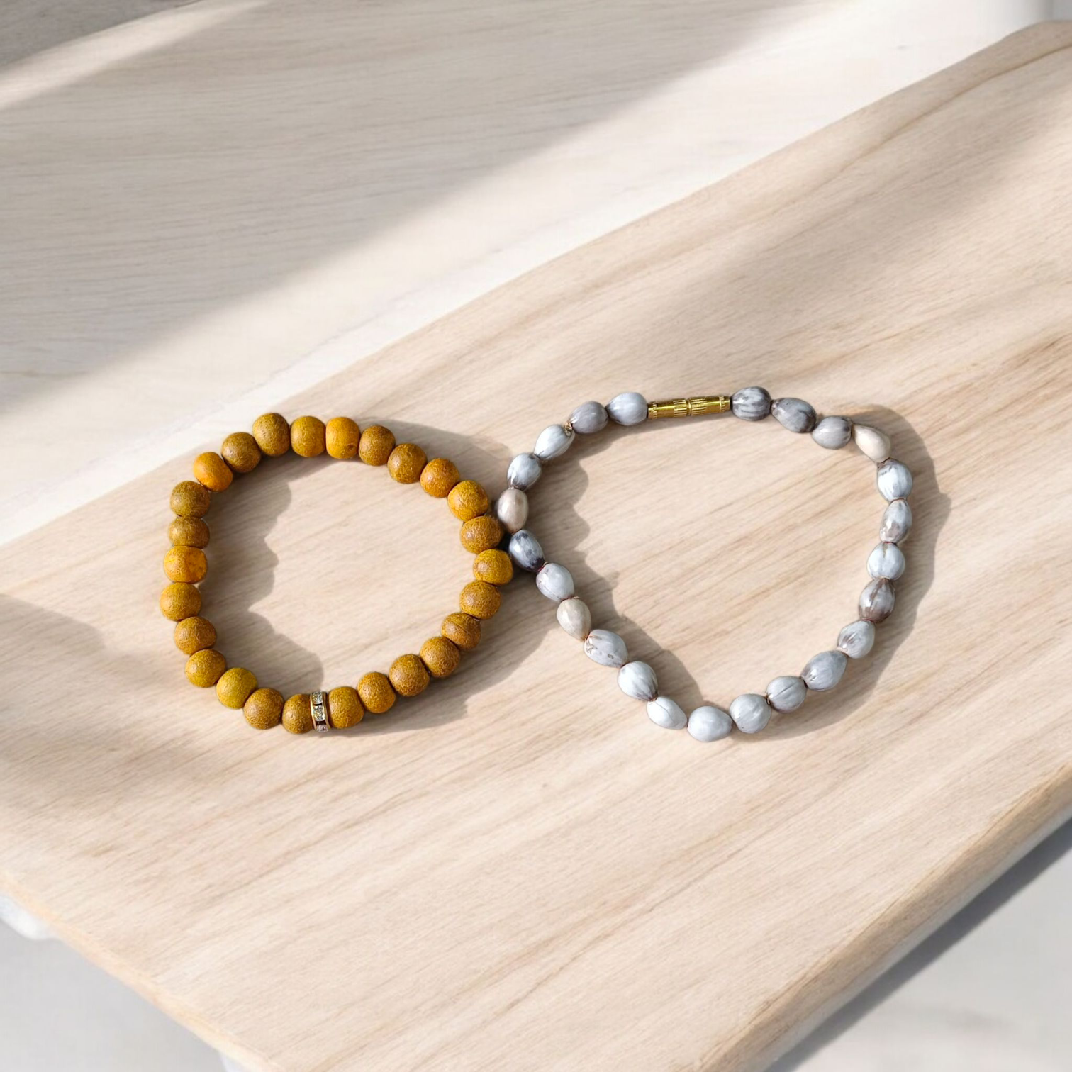 Image of two stretchable bracelets – one made with white Vaijanti seeds and one with yellow Haldi beads – arranged side by side on a natural background