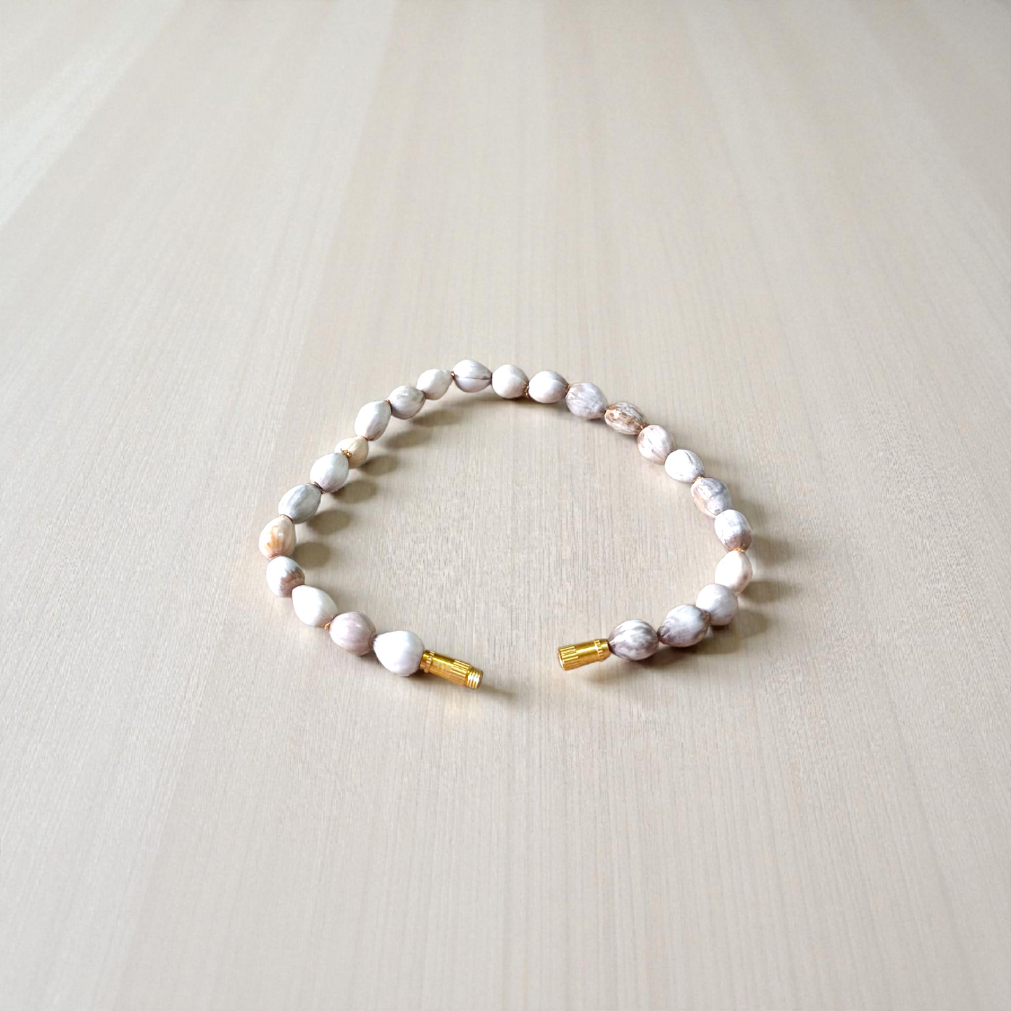 Image of two stretchable bracelets – one made with white Vaijanti seeds and one with yellow Haldi beads – arranged side by side on a natural background
