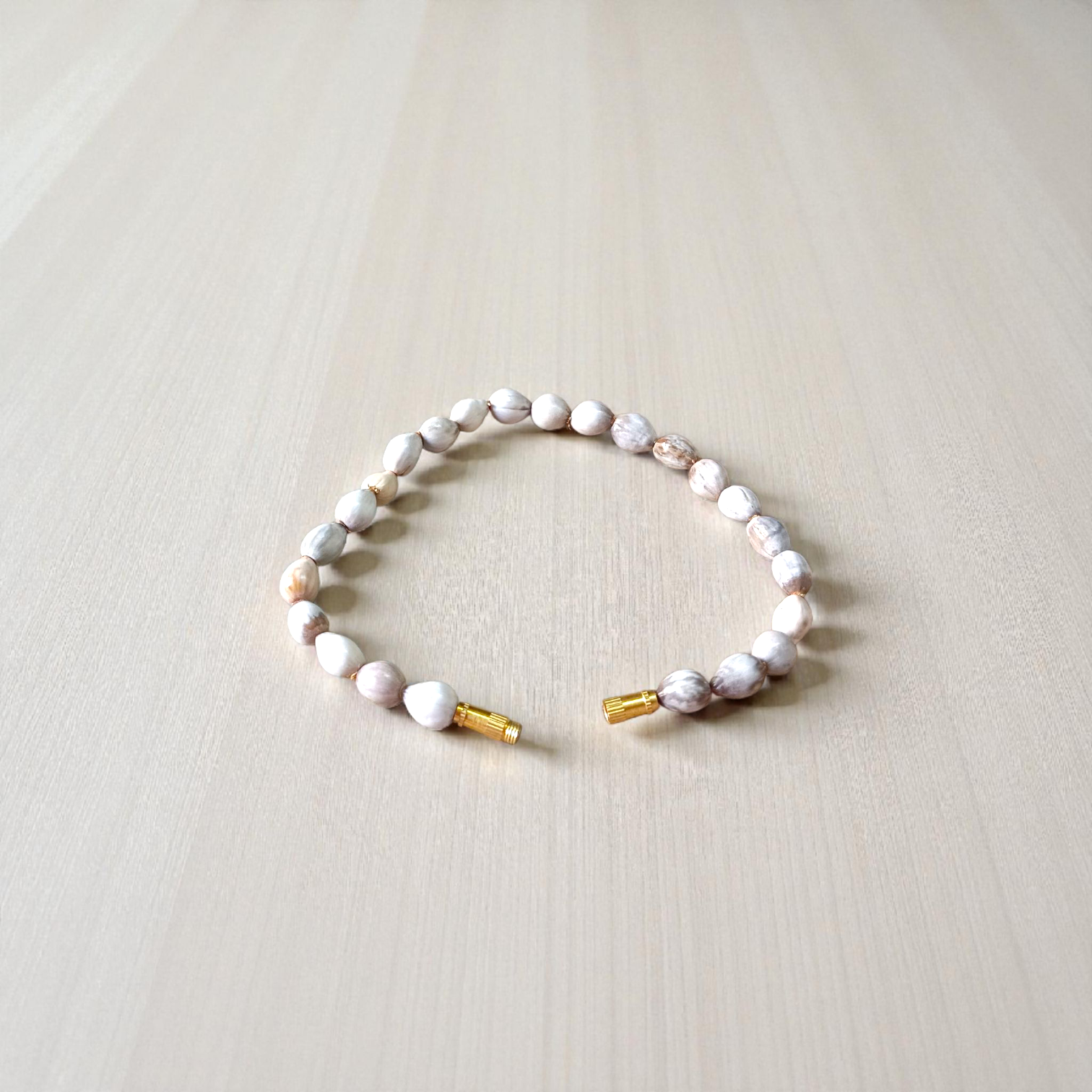 Image of two stretchable bracelets – one made with white Vaijanti seeds and one with yellow Haldi beads – arranged side by side on a natural background
