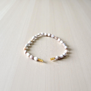 Image of two stretchable bracelets – one made with white Vaijanti seeds and one with yellow Haldi beads – arranged side by side on a natural background
