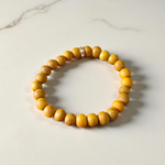 Image of two stretchable bracelets – one made with white Vaijanti seeds and one with yellow Haldi beads – arranged side by side on a natural background