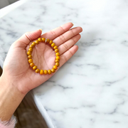 Image of two stretchable bracelets – one made with white Vaijanti seeds and one with yellow Haldi beads – arranged side by side on a natural background