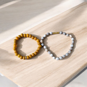 Image of two stretchable bracelets – one made with white Vaijanti seeds and one with yellow Haldi beads – arranged side by side on a natural background