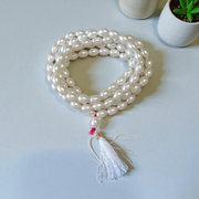 Image showing a hand-knotted Moti Mala made of smooth, white natural pearls with a central guru bead, placed on a sacred cloth for worship