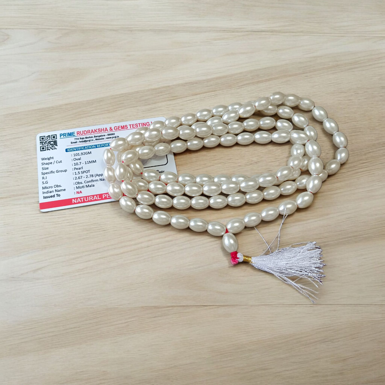 Image showing a hand-knotted Moti Mala made of smooth, white natural pearls with a central guru bead, placed on a sacred cloth for worship