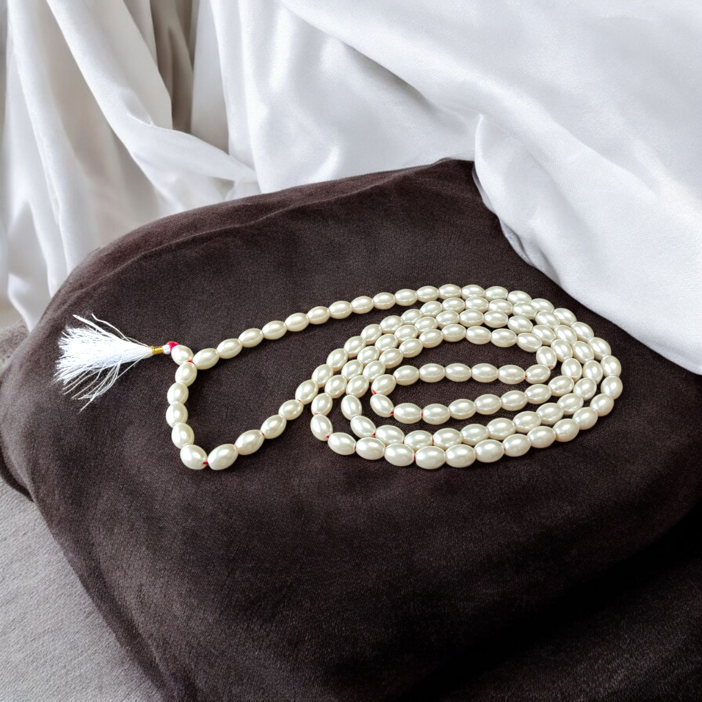 Image showing a hand-knotted Moti Mala made of smooth, white natural pearls with a central guru bead, placed on a sacred cloth for worship