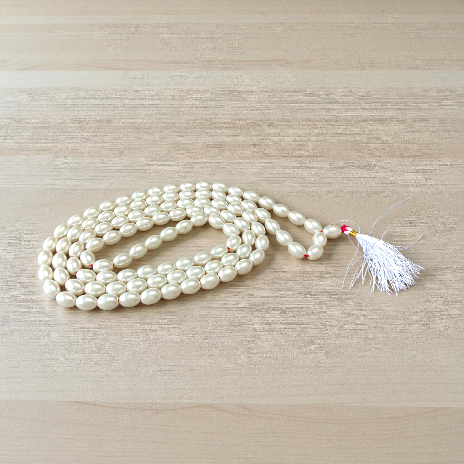 Image showing a hand-knotted Moti Mala made of smooth, white natural pearls with a central guru bead, placed on a sacred cloth for worship