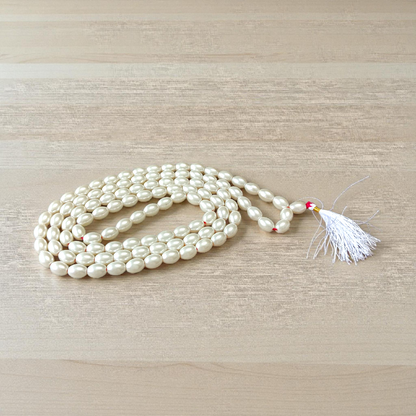 Image showing a hand-knotted Moti Mala made of smooth, white natural pearls with a central guru bead, placed on a sacred cloth for worship