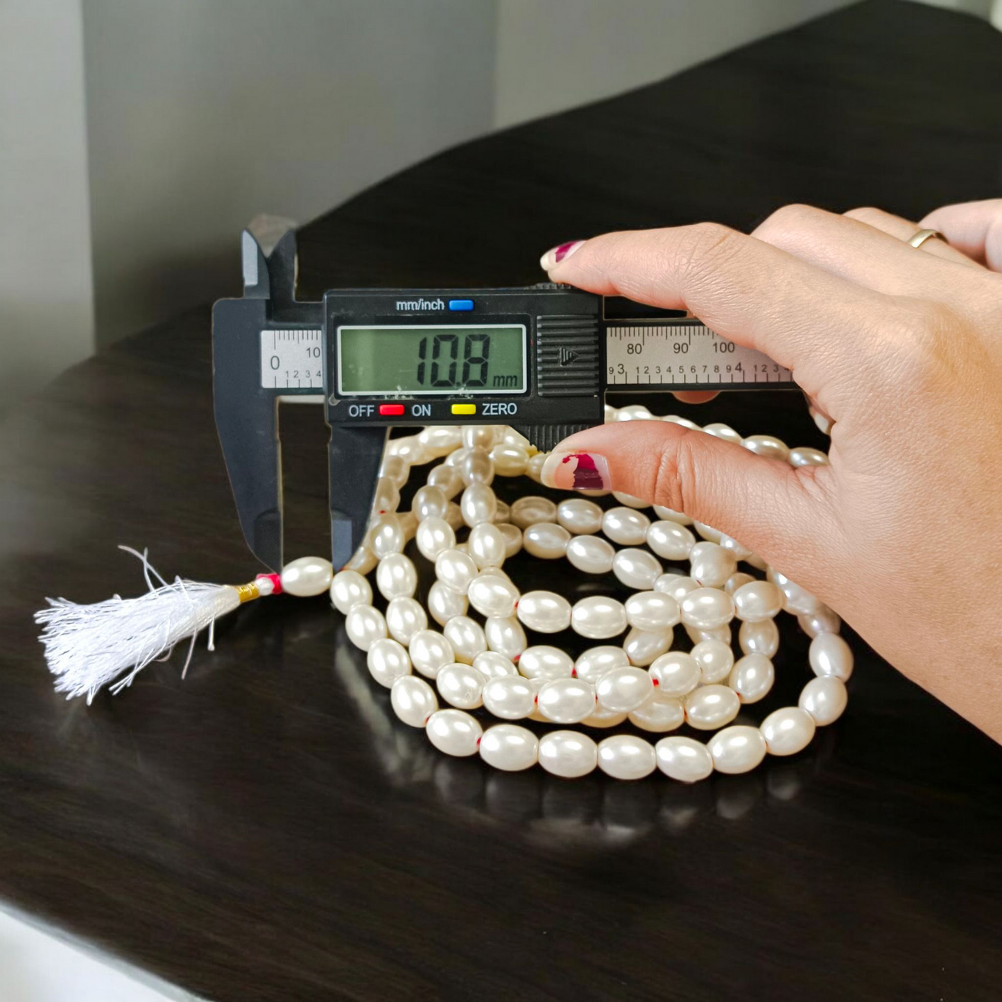Image showing a hand-knotted Moti Mala made of smooth, white natural pearls with a central guru bead, placed on a sacred cloth for worship