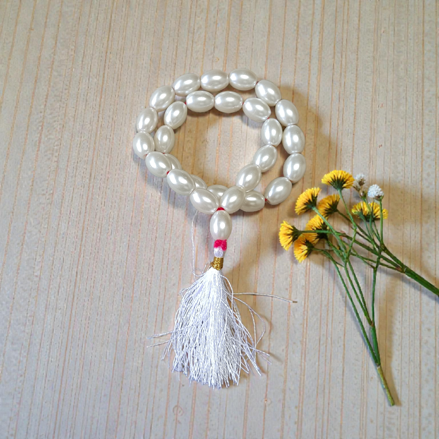 Image showing a hand-knotted Moti Mala made of smooth, white natural pearls with a central guru bead, placed on a sacred cloth for worship