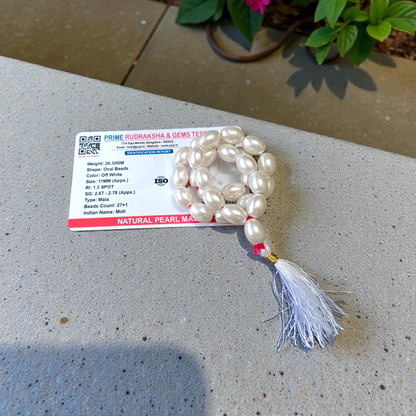 Image showing a hand-knotted Moti Mala made of smooth, white natural pearls with a central guru bead, placed on a sacred cloth for worship