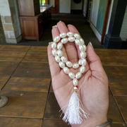 Image showing a hand-knotted Moti Mala made of smooth, white natural pearls with a central guru bead, placed on a sacred cloth for worship
