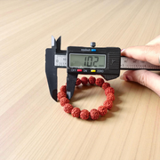 Image showing a stretchable 5 Mukhi Rudraksha bracelet made with 11mm natural brown beads, arranged in a circle on a plain background