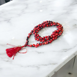 Image showing combo of Lal Gunja Mala and Black Gunja Mala with 108+1 beads, lab certified, placed aesthetically on a spiritual cloth for rituals or meditation