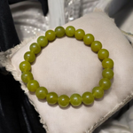 Light green onyx bracelet with 8mm round beads, stretchable elastic design, displayed on a wooden surface