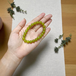 Light green onyx bracelet with 8mm round beads, stretchable elastic design, displayed on a wooden surface