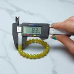 Light green onyx bracelet with 8mm round beads, stretchable elastic design, displayed on a wooden surface