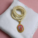 Moti mala with white pearls and Radha Krishna locket placed on a velvet cloth background
