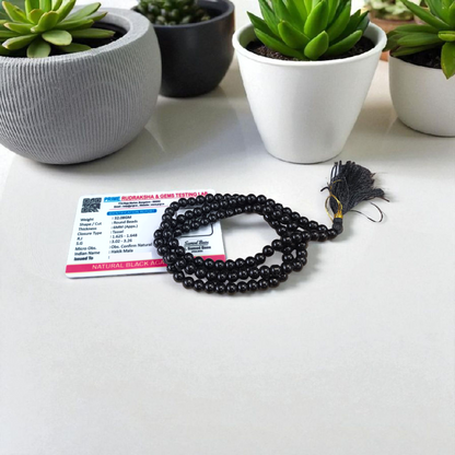 Natural Black Agate (Hakik) Mala made of 6mm smooth beads, coiled neatly with a Guru bead on a light background