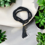 Natural Black Agate (Hakik) Mala made of 6mm smooth beads, coiled neatly with a Guru bead on a light background