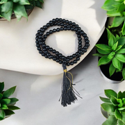 Natural Black Agate (Hakik) Mala made of 6mm smooth beads, coiled neatly with a Guru bead on a light background