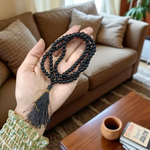 Natural Black Agate (Hakik) Mala made of 6mm smooth beads, coiled neatly with a Guru bead on a light background