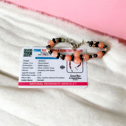 Natural Hessonite Bracelet with polished round beads on elastic cord, lab certified, placed on a wooden surface