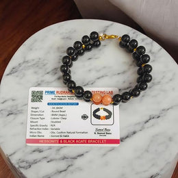 Natural Hessonite (Gomed) and Black Agate (Hakik) gemstone bracelet placed on a white background with a MALAWALA certification card beside it