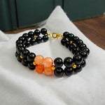 Natural Hessonite (Gomed) and Black Agate (Hakik) gemstone bracelet placed on a white background with a MALAWALA certification card beside it