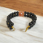 Natural Hessonite (Gomed) and Black Agate (Hakik) gemstone bracelet placed on a white background with a MALAWALA certification card beside it
