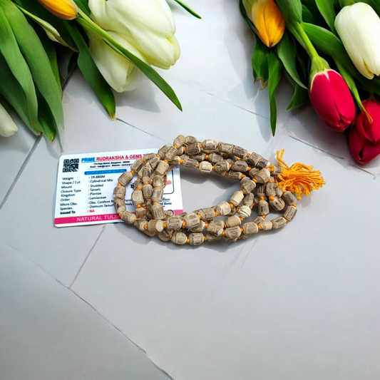 Natural Tulsi Kantha Mala with large round beads, arranged neatly with a central Guru bead on a wooden background